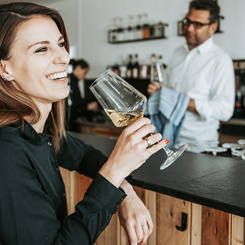 Frau lächelt und hält ein Weinglas in der Hand.