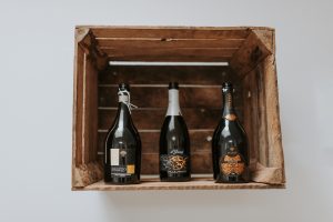 Drei leere Flaschen in einer Holzkiste an der Wand hängend